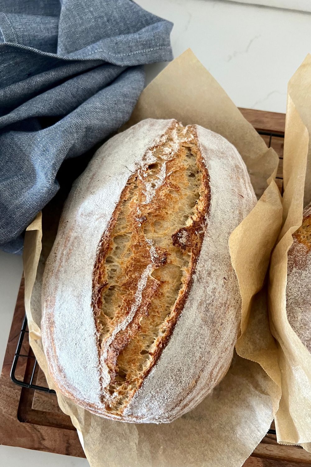 A loaf of sourdough bread cooling on a wire rack.